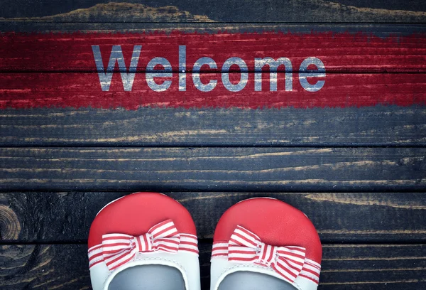 Mensaje de bienvenida y zapatos de niño en el suelo — Foto de Stock