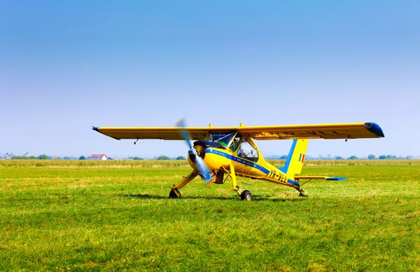 Retro yellow airplane on a green grass field preparing to take o — Stock Photo, Image