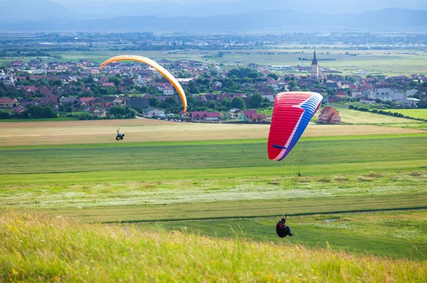 Parapentes volando sobre campos verdes — Foto de Stock