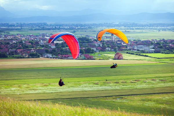 Paragliders vliegen over de groene velden — Stockfoto