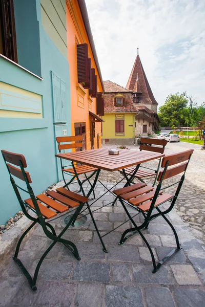 Tafel met stoelen op steen geplaveid oude straat en gekleurde huizen f — Stockfoto
