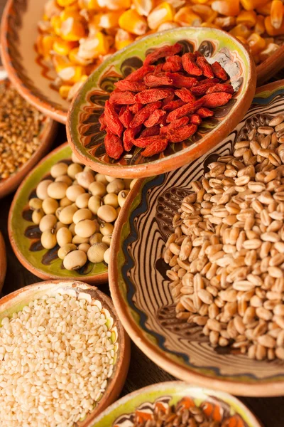 Various grain beans in small clay plates on natural textured woo — Stock Photo, Image