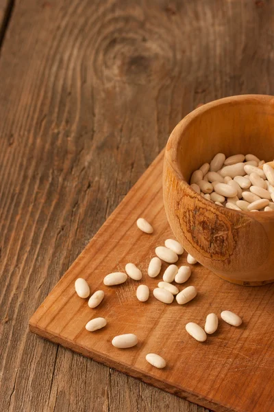 Bonen in een houten pot op natuurlijke gestructureerde hout achtergrond — Stockfoto