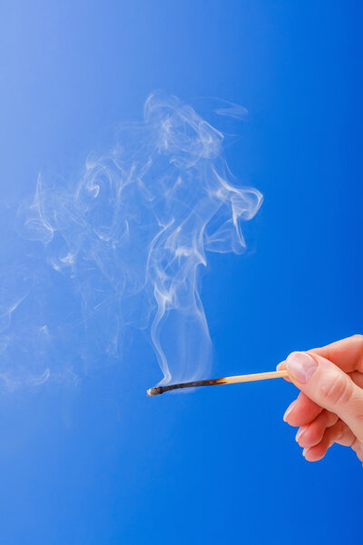 Hand holding burnt fuming matchstick