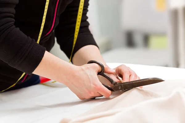 Dressmaker cutting fabric with scissors — Stock Photo, Image