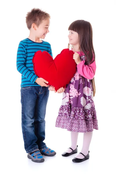 Meisje en jongen houden een grote rode hart vormige kussen — Stockfoto