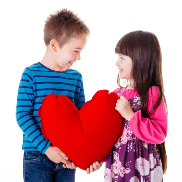 Retrato de menina e menino segurando um grande travesseiro em forma de coração vermelho — Fotografia de Stock