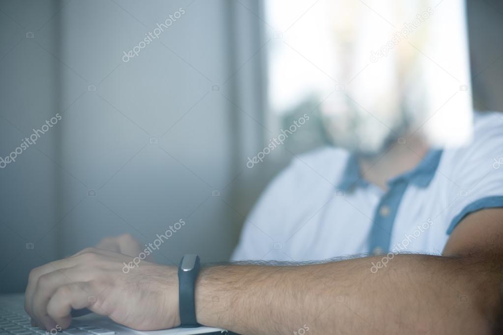 man with fitness tracker in the office through glass window