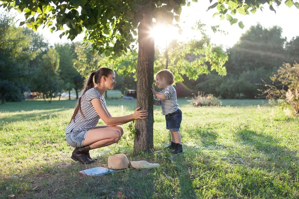 Madre y niño sentado bajo el árbol durante las vacaciones de verano —  Fotos de Stock