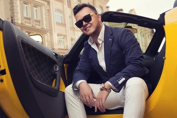 Stylish man posing with convertible sportcar