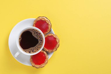 Sarı arka planda marmelatlı kahve ve kurabiye, fotokopi alanı olan üst manzara.
