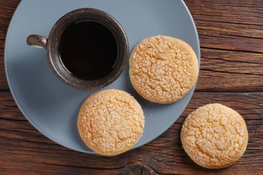 Bir fincan kahve ve kurabiye. Masanın üstünde şeker var. Yakın plan.