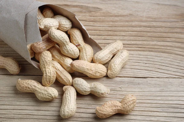 Erdnüsse Aus Einer Papiertüte Auf Holzgrund Verstreut — Stockfoto