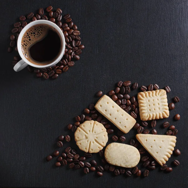 黒の石の背景に様々なショートブレッドクッキーとコーヒーカップ トップビュー — ストック写真
