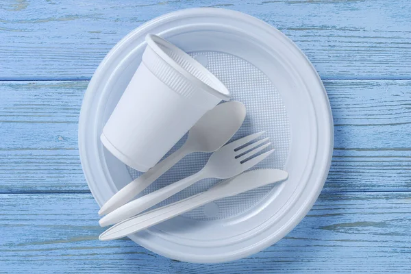 Disposable tableware and cutlery on blue wooden table, top view