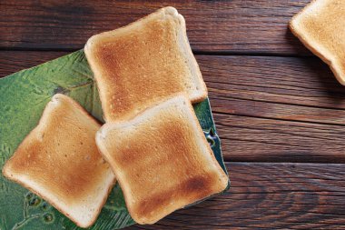 Tahta zemin üzerinde yeşil seramik tahta üzerinde kızarmış ekmek dilimleri, üst görünüm