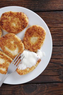 Kızarmış ev yapımı süzme peynirli krep ahşap bir masada ekşi krema.