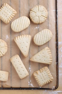 Mutfak masasındaki kahverengi kabartma kağıdında çeşitli kurabiyeler, üst manzara.