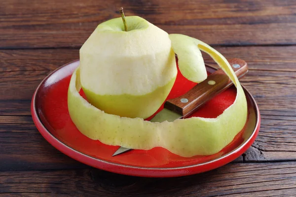 Ξεφλουδισμένο Πράσινο Μήλο Και Μαχαίρι Κόκκινο Πιάτο Ξύλινο Τραπέζι — Φωτογραφία Αρχείου