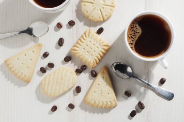 Masada iki fincan kahve ve çeşitli kurabiyeler var.