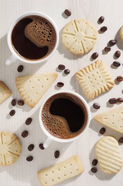 Çeşitli kurabiyeler ve masanın üstünde iki fincan kahve.