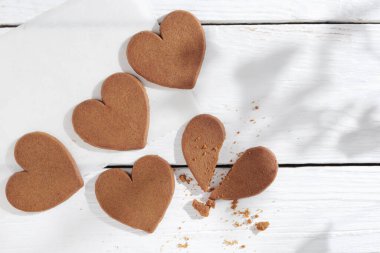 Beyaz ahşap masada kalp şeklinde zencefilli kurabiyeler.