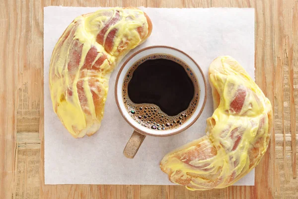 Buns with lemon cream and cup of coffee on old wooden background, top view