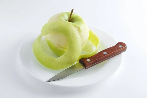 Peeled Πράσινο Μήλο Και Μαχαίρι Ένα Πιάτο Λευκό Φόντο — Φωτογραφία Αρχείου