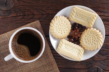 Kurabiye ve bir fincan kahve. Koyu ahşap masada, üst tarafta.