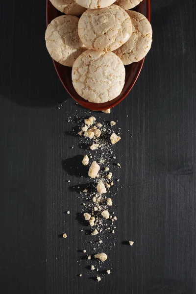 Italian almond cookies with crumbs on black wooden background or table, top view