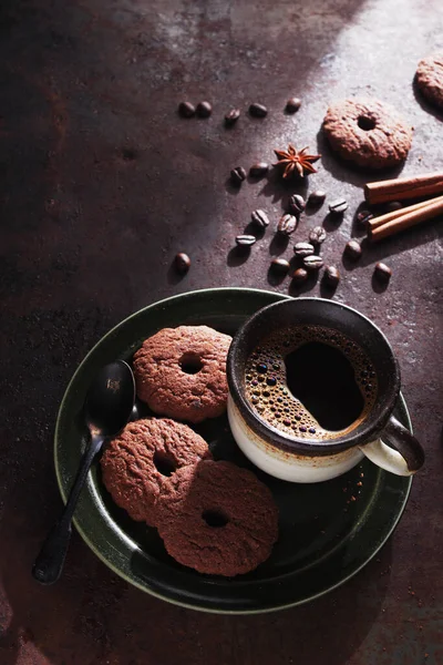 Cookies cocoa rings and cup of coffee on a plate on rustic background, high angle view