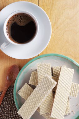 Kahvaltı için bir fincan kahve ve lezzetli gofretler masanın üstünde. 