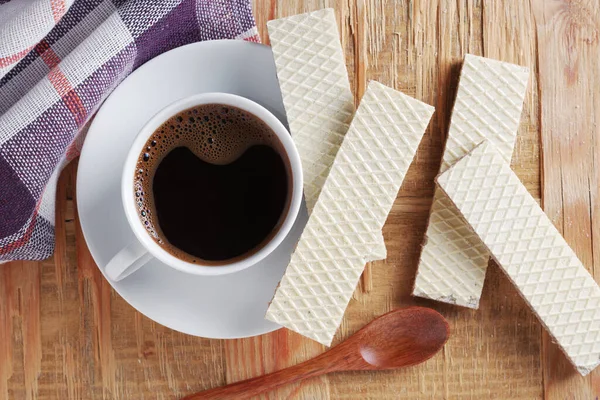 Cup of coffee with wafers on old wooden background or table, top view. Still life for breakfast