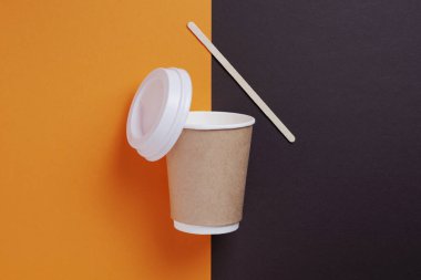 İki tonluk arka planda kapağı ve samanı olan tek kullanımlık içecek bardağı, üst görünüm