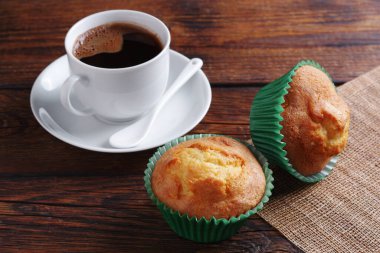 Kırsal ahşap masada iki fincan kek ve bir fincan kahve yakın.