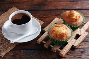 Bir fincan kahve ve kekler kırsal ahşap masada.