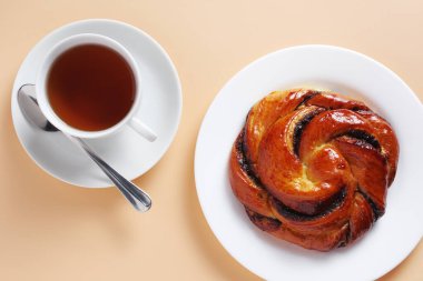 Kahvaltınız için bej arka planda bir fincan çörek ve çay.