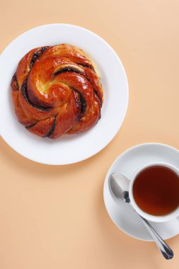 Bej arka planda tatlı çörek ve çay, üst manzara.