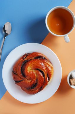 İki tonlu arka planda çörek ve bir fincan çay, üst manzara.