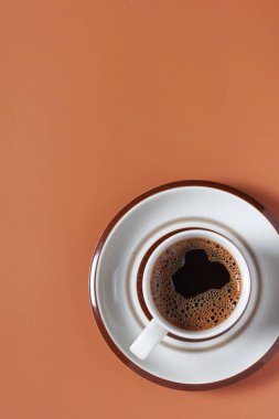 Kahverengi arka planda bir fincan kahve, fotokopi alanı ile üst manzara