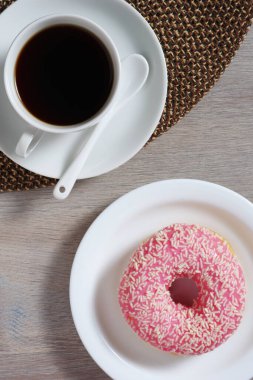 Masada servis edilen sıcak kahve ve üzerine pembe çörekler, üst manzara.