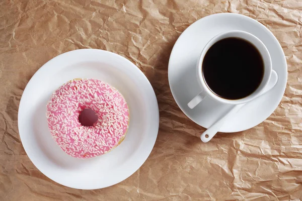 粉红甜甜圈与洒水和咖啡在皱折的纸张背景 顶部视图 — 图库照片