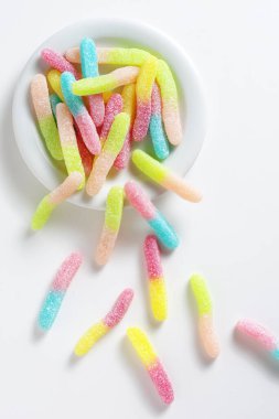 Beyaz arka planda tabakta meyveli şeker solucanları, üst manzara.