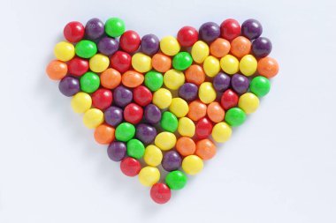 Beyaz arka planda kalp şeklinde renkli şekerlemeler, üst görünüm