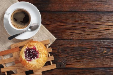 Bir fincan kahve ve ahşap masada reçelli lezzetli çörek, fotokopi alanı olan üst manzara.