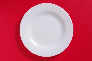 Kırmızı zemin üzerinde boş beyaz seramik plaka, üst görünüm