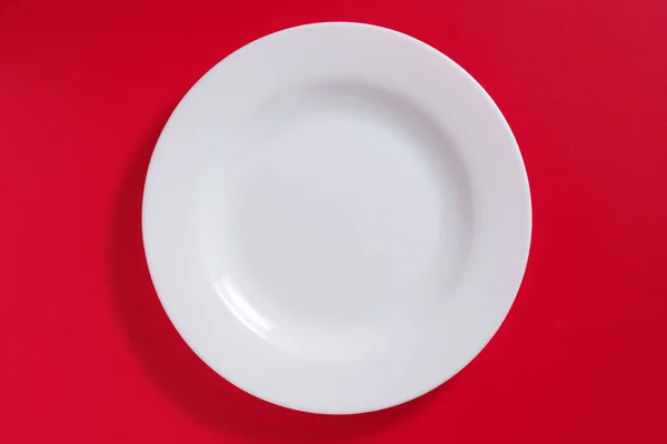 Κενό Λευκό Κεραμικό Πιάτο Κόκκινο Φόντο Πάνω Όψη — Φωτογραφία Αρχείου