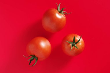 Kırmızı zemin üzerinde taze domatesler, üst görünüm
