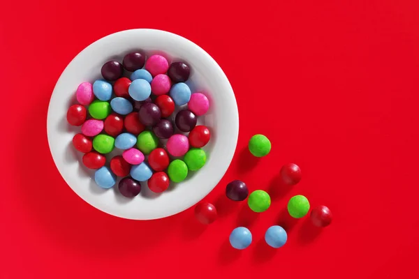 Πολύχρωμες Καραμέλες Skittles Στο Πιάτο Ένα Κόκκινο Φόντο Κορυφαία Προβολή — Φωτογραφία Αρχείου