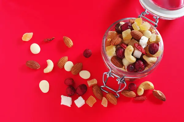 異なるナッツと砂糖漬けの果物の混合物は 赤の背景に朝食のために トップビュー — ストック写真
